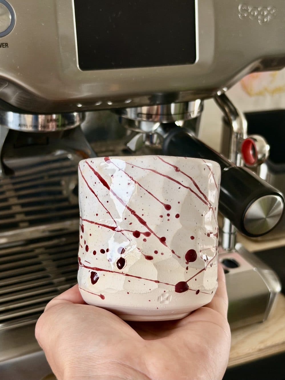Weißer Becher mit roten Glasurspritzern